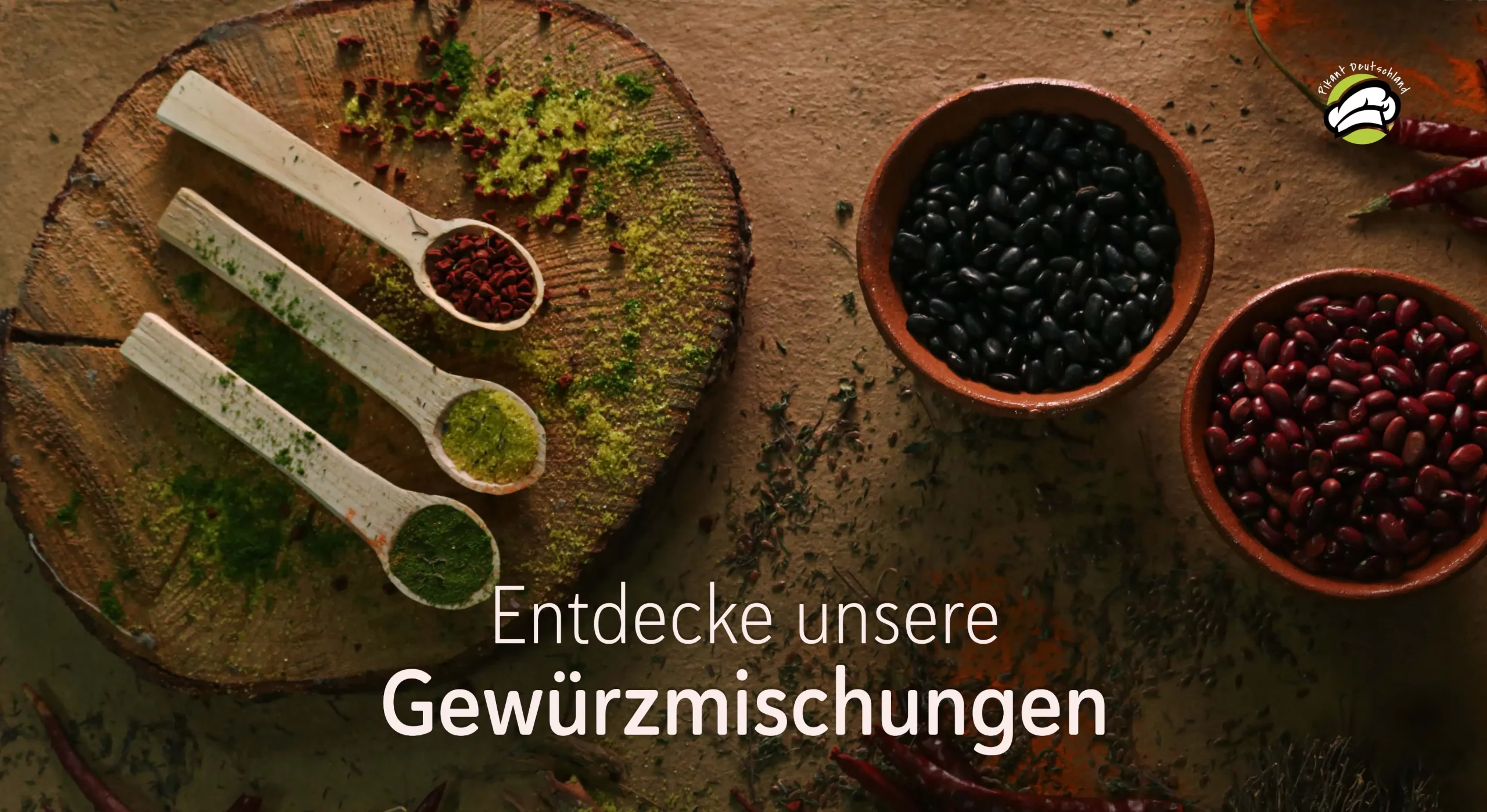 Entdecke unsere Gewürzmischungen – drei Holzlöffel mit aromatischen Gewürzen auf rustikalem Holzuntergrund. Begleitend dazu zwei Schalen mit schwarzen und roten Bohnen. Der Schriftzug 'Entdecke unsere Gewürzmischungen' lädt zur kulinarischen Vielfalt ein. Markenlogo 'Pikant Deutschland' in der oberen rechten Ecke.